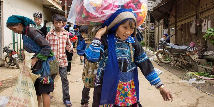 Children carry goods down a village street.