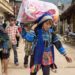 Children carry goods down a village street.
