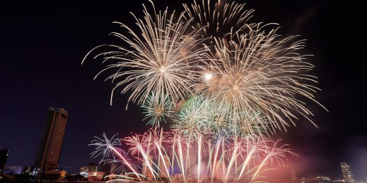 fireworks are lit up in the night sky over a body of water