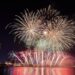 fireworks are lit up in the night sky over a body of water