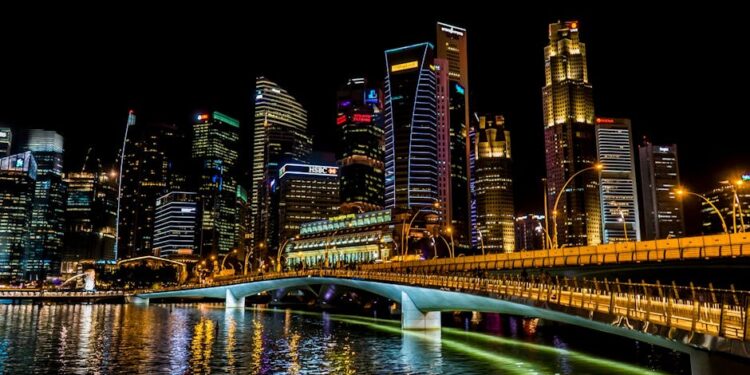 Stunning Singapore cityscape featuring vibrant skyscrapers, illuminated bridge, and reflections over the river at night.