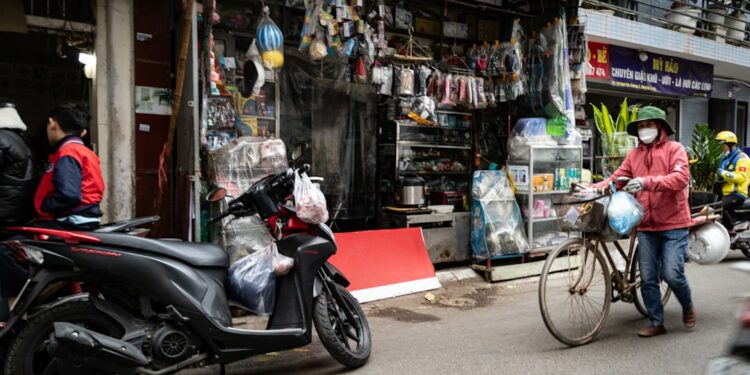 Woman with bicycle walks past a street shop