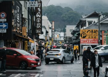 a group of people walking down a street next to tall buildings
