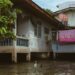 a bird standing in a flooded area next to a house
