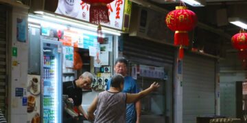 People at a brightly lit street food stall with lanterns