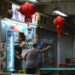 People at a brightly lit street food stall with lanterns