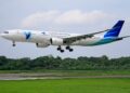 Garuda Indonesia Airbus A330 aircraft landing on a runway surrounded by greenery.