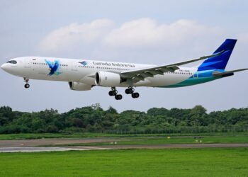 Garuda Indonesia Airbus A330 aircraft landing on a runway surrounded by greenery.