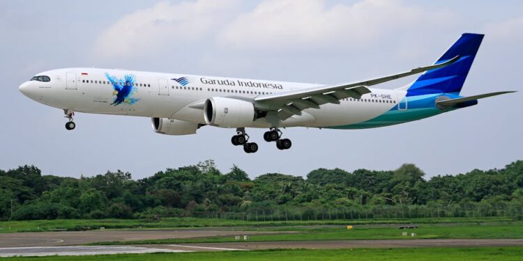 Garuda Indonesia Airbus A330 aircraft landing on a runway surrounded by greenery.