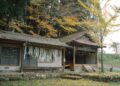 Explore a serene traditional Japanese house surrounded by vibrant autumn foliage, capturing the essence of rural Japan.