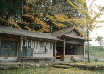 Explore a serene traditional Japanese house surrounded by vibrant autumn foliage, capturing the essence of rural Japan.