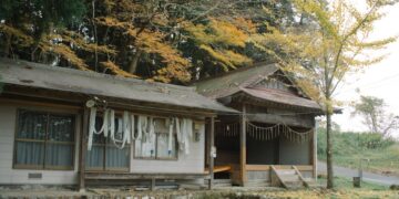 Explore a serene traditional Japanese house surrounded by vibrant autumn foliage, capturing the essence of rural Japan.