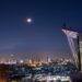 Stunning view of Bangkok's skyline under a full moon, capturing urban lights and architecture.