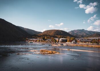 Beautiful landscape of Arashiyama mountains and river in Kyoto, Japan, under a clear blue sky.