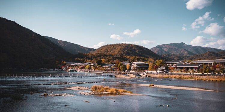 Beautiful landscape of Arashiyama mountains and river in Kyoto, Japan, under a clear blue sky.