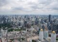 Stunning aerial view of Bangkok's modern skyline under clouded skies.