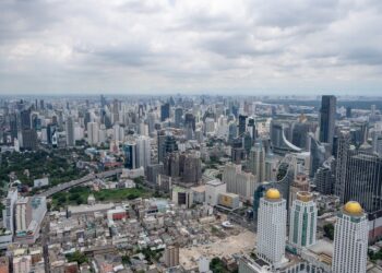 Stunning aerial view of Bangkok's modern skyline under clouded skies.