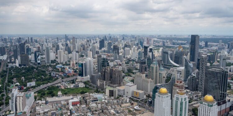 Stunning aerial view of Bangkok's modern skyline under clouded skies.