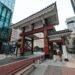 Street view of a traditional Japanese gate amidst modern Tokyo architecture.
