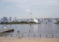 A serene day view of Rainbow Bridge and Tokyo skyline from Minato City waterfront.