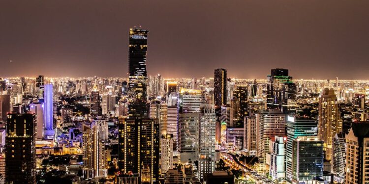 A vibrant night view of Bangkok's illuminated skyline featuring modern skyscrapers.