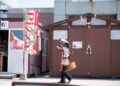 A person in traditional attire walks past a pizza sign in Hokkaido, Japan.