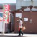 A person in traditional attire walks past a pizza sign in Hokkaido, Japan.