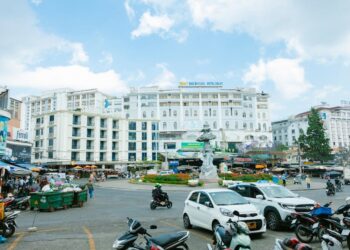 Vibrant street scene in Đà Lạt, Vietnam, showcasing hotels, traffic, and city life under a clear sky.