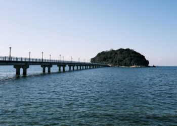 A serene ocean view featuring a bridge leading to an island in Gamagōri, Japan.