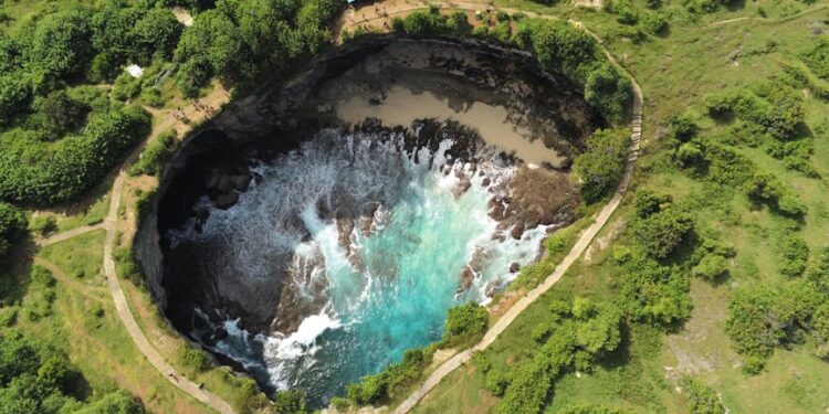 A breathtaking aerial view of Angel's Billabong in Nusa Penida, Bali showcasing vibrant turquoise waters in a rocky inlet.
