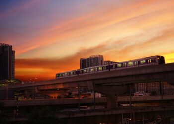 Elevated train against a dramatic sunset sky in Bangkok, representing urban transport in Thailand.