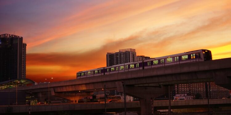 Elevated train against a dramatic sunset sky in Bangkok, representing urban transport in Thailand.