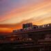Elevated train against a dramatic sunset sky in Bangkok, representing urban transport in Thailand.