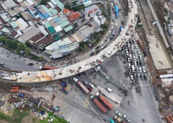 Aerial view of Ho Chi Minh City showcasing busy traffic around ongoing bridge construction.