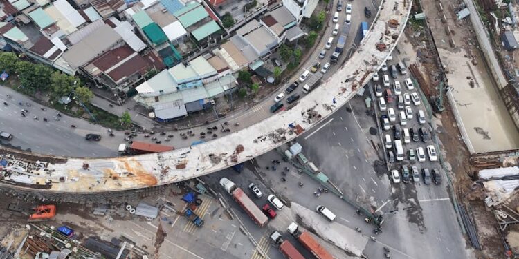 Aerial view of Ho Chi Minh City showcasing busy traffic around ongoing bridge construction.