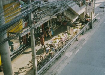 Aerial view of a bustling street market in Bangkok with bikes and vendors.