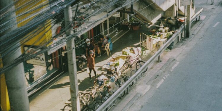 Aerial view of a bustling street market in Bangkok with bikes and vendors.