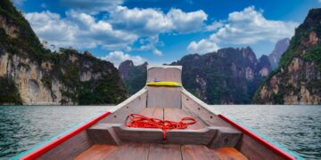 A peaceful boat ride through the scenic limestone cliffs of Khao Sok National Park, Thailand.