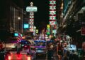 Vibrant night scene in Bangkok's Chinatown with tuk-tuks and neon lights.