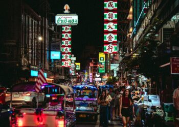 Vibrant night scene in Bangkok's Chinatown with tuk-tuks and neon lights.