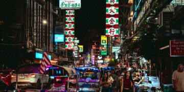 Vibrant night scene in Bangkok's Chinatown with tuk-tuks and neon lights.