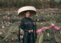 A woman in a traditional Vietnamese outfit stands in a vibrant lotus field, showcasing cultural elegance.