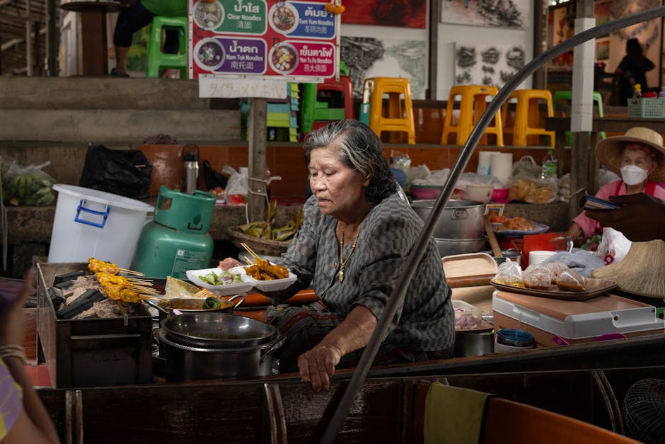 Stand de street food thaïlandaise avec pad thai préparé au wok sur un marché nocturne