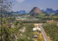 Scenic aerial view of Ao Nang, Thailand, featuring mountains, palm groves, and rural areas.