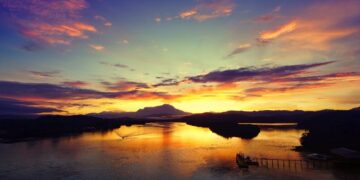 Mesmerizing sunset over a river in Tuaran, Sabah, Malaysia with vibrant sky and reflections.
