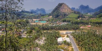 Scenic aerial view of Ao Nang, Thailand, featuring mountains, palm groves, and rural areas.