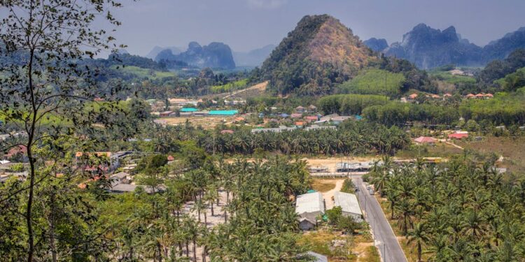 Scenic aerial view of Ao Nang, Thailand, featuring mountains, palm groves, and rural areas.