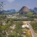 Scenic aerial view of Ao Nang, Thailand, featuring mountains, palm groves, and rural areas.