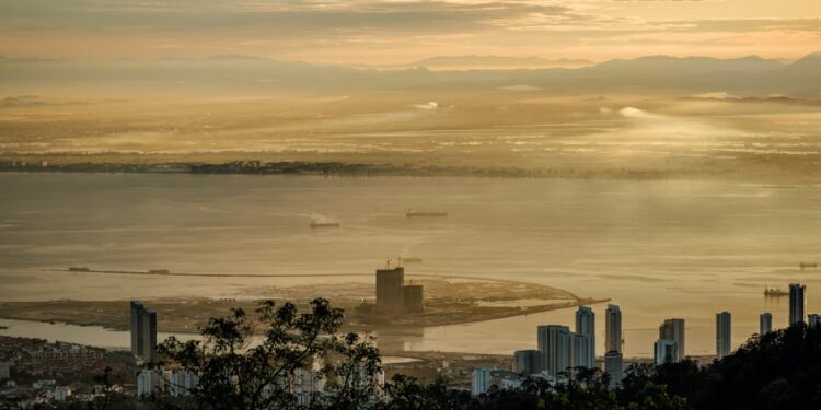 Stunning sunrise view over Penang from Bukit Bendera, Malaysia featuring skyscrapers and the coastline.