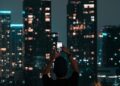 A person photographing Jakarta's illuminated skyscrapers during a vibrant city night.